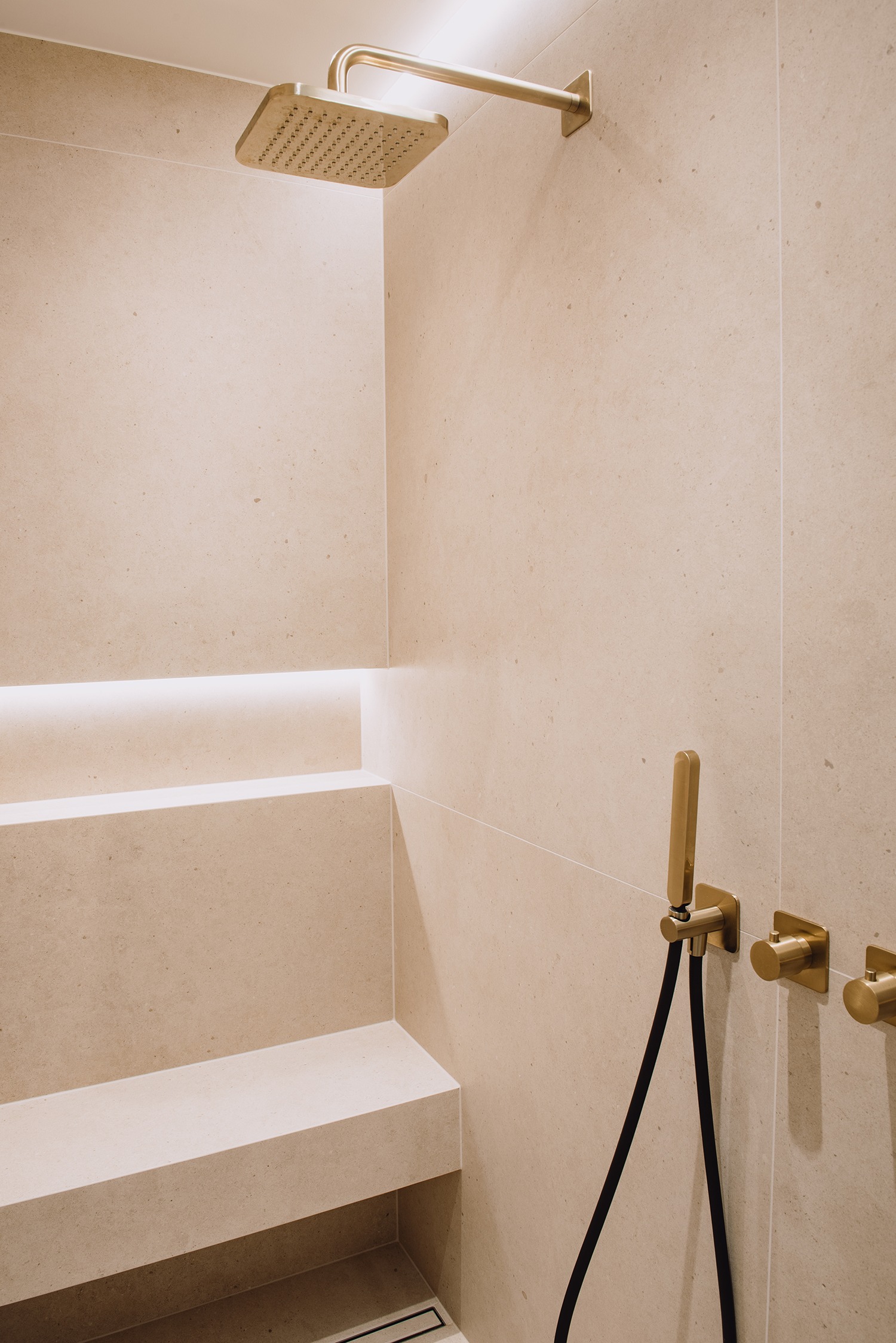 Natuurstenen douche met nis, zitbank en messing armaturen