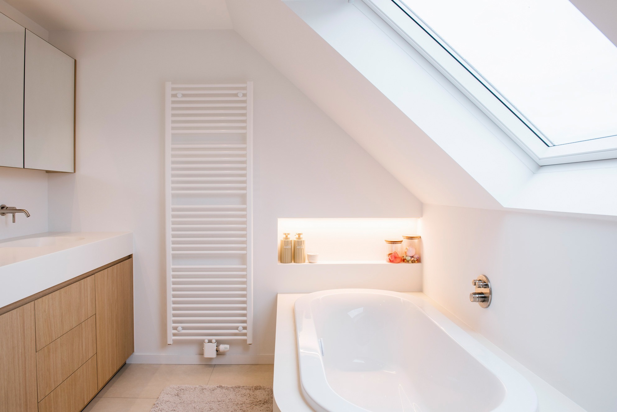 Lichte badkamer van House DP met houten wastafelmeubel onder het daklicht