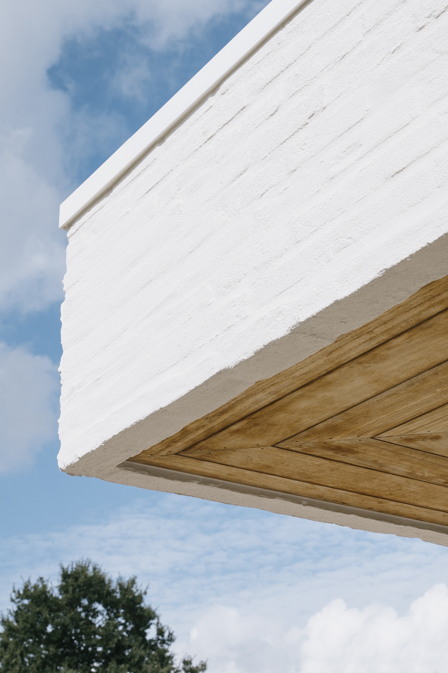 Detail van witte baksteen en de houten luifelrand tegen de lucht