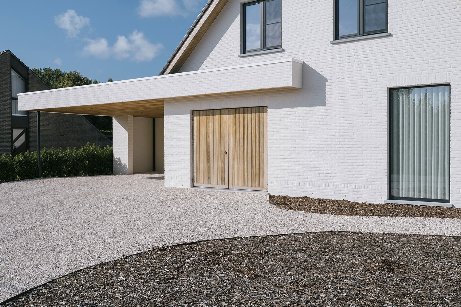 House DP met witgeschilderde baksteen, houten deur en brede horizontale luifel