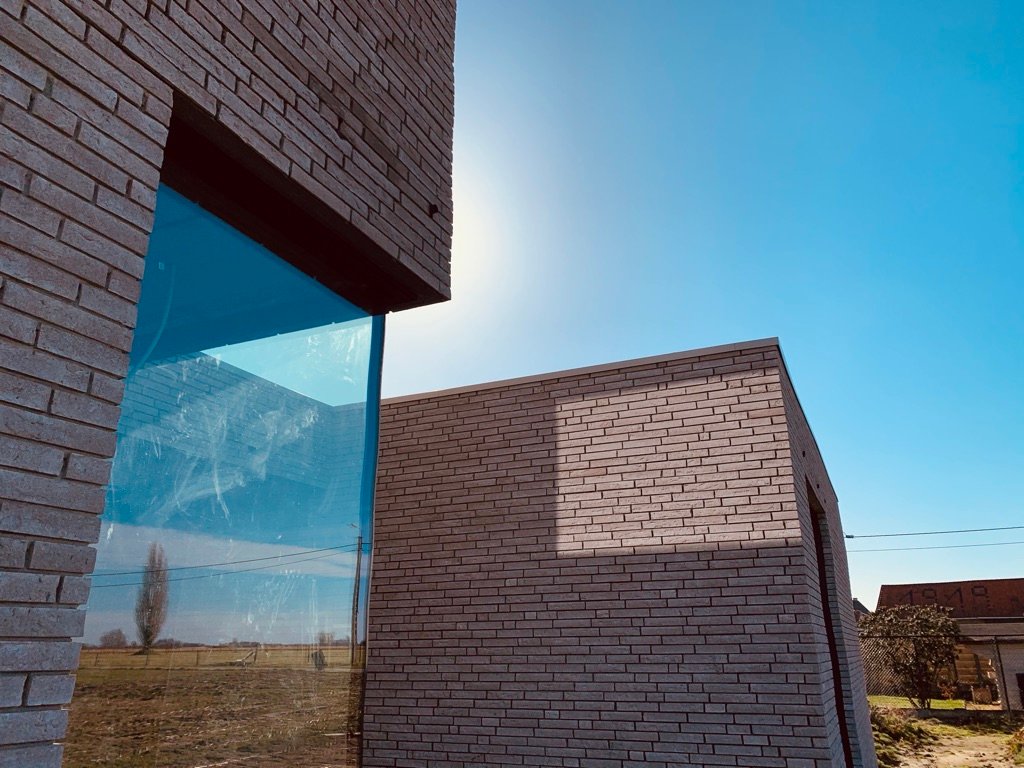 Bakstenen volumes van House M tegen de blauwe hemel