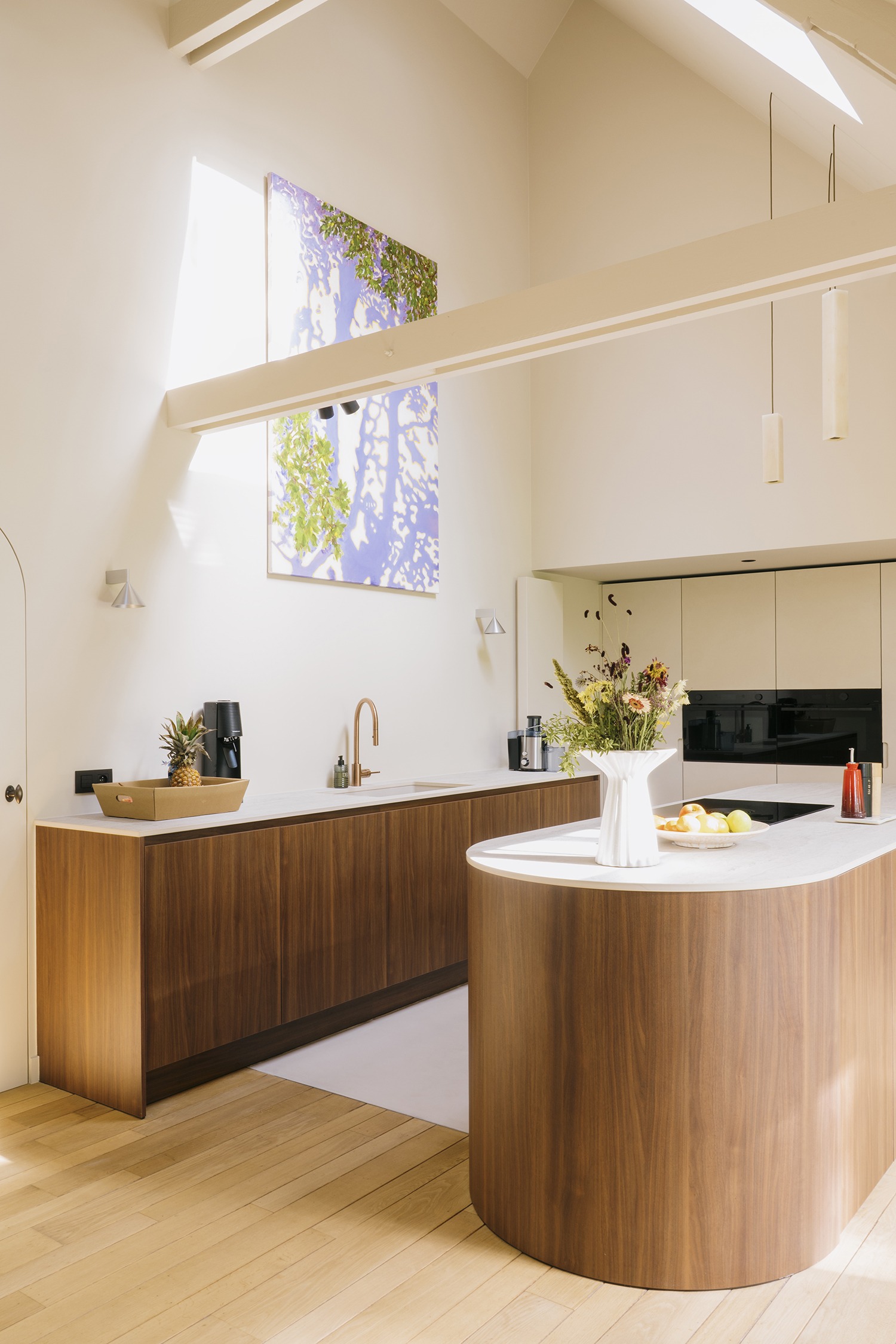 Gebogen houten keukeneiland onder het open dakvolume