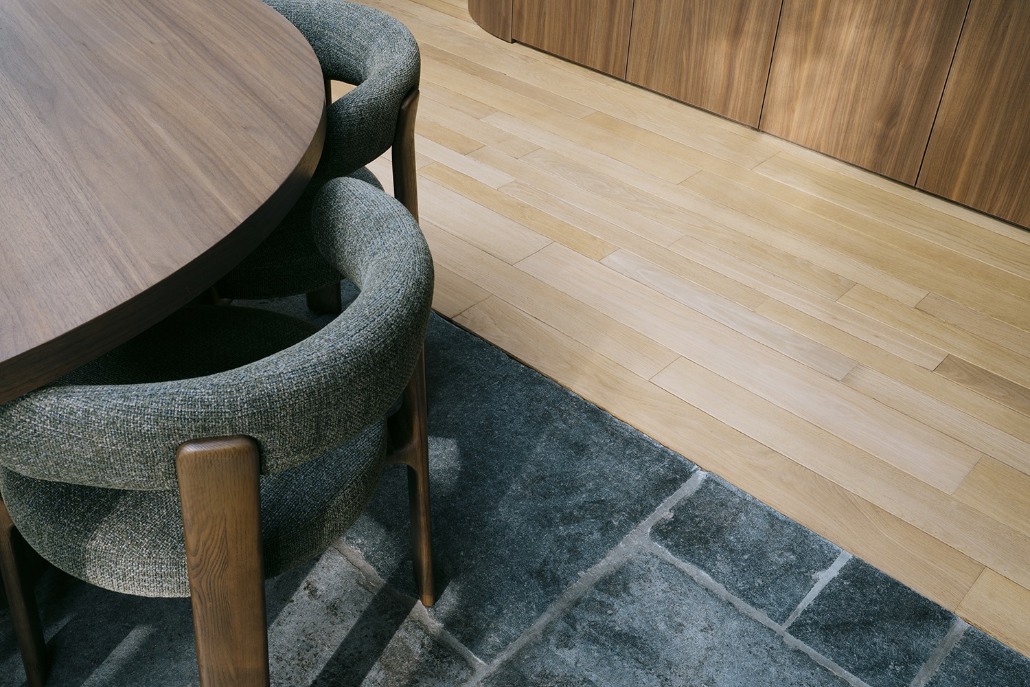Detail van de houten tafel, gestoffeerde stoelen en natuurstenen vloer